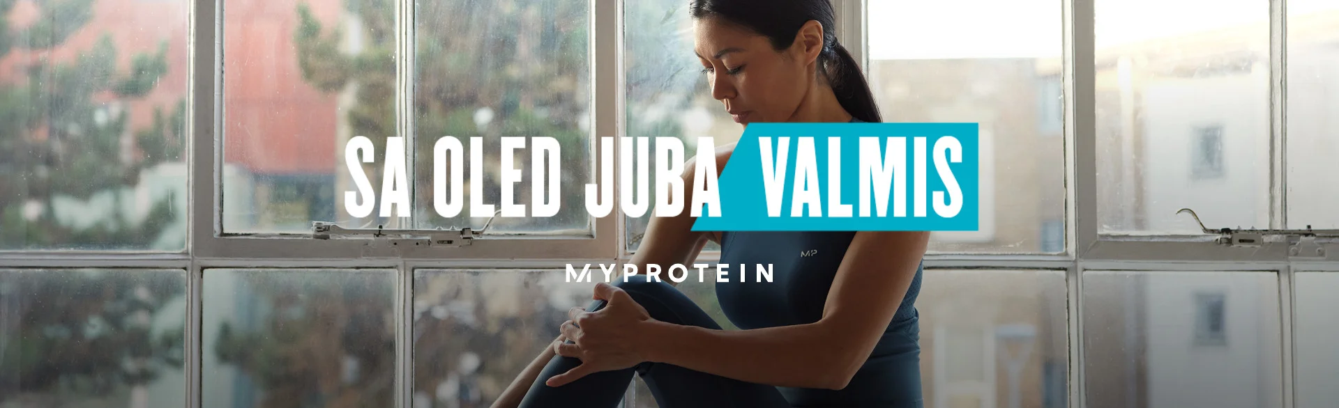 A woman wearing MP gym clothing sat on a window ledge stretching with the text 'You're Already Ready - MYPROTEIN' overlaying the image.